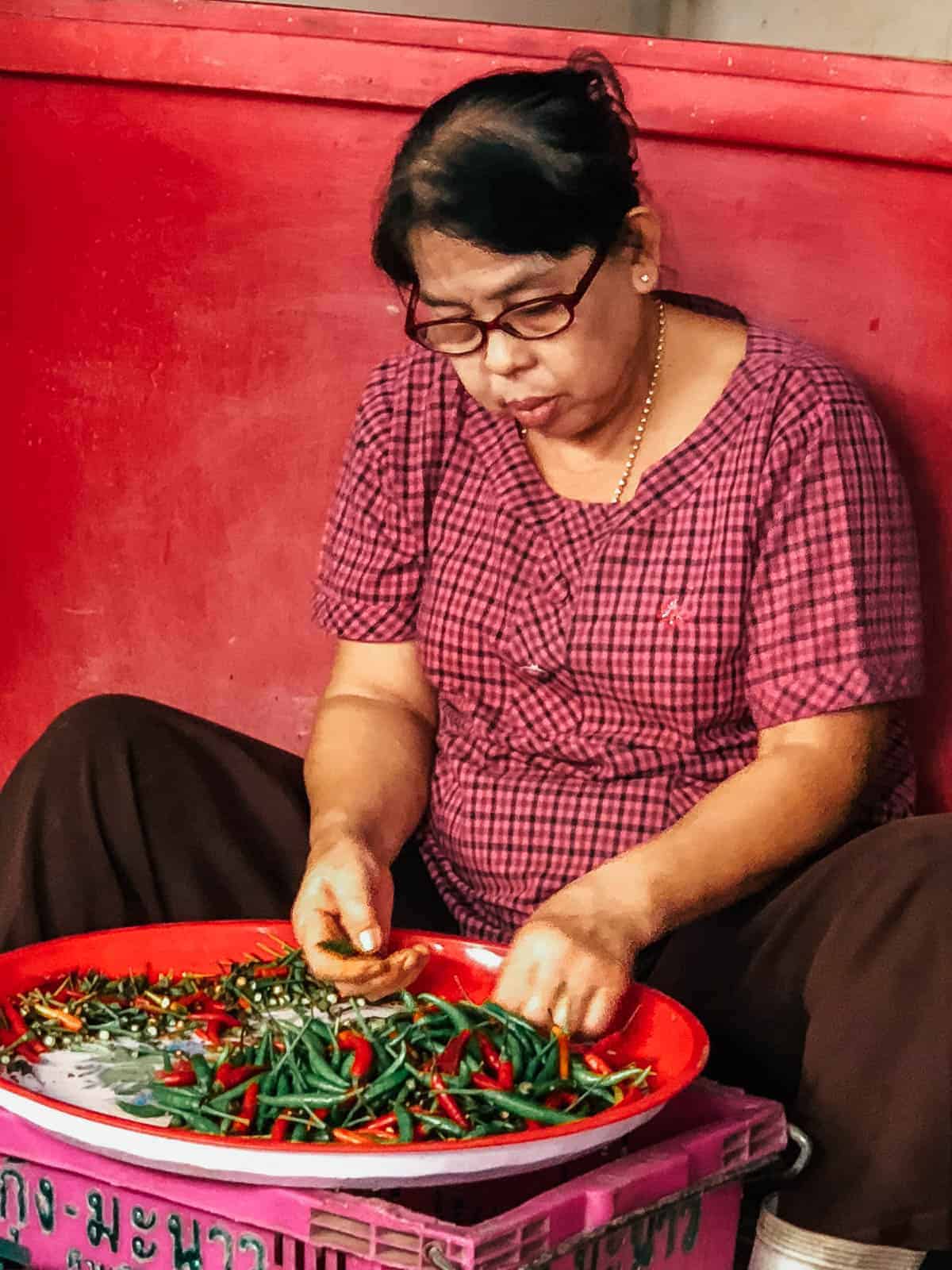 Woman sorting vegetables at a stall at Maeklong market in Bangkok