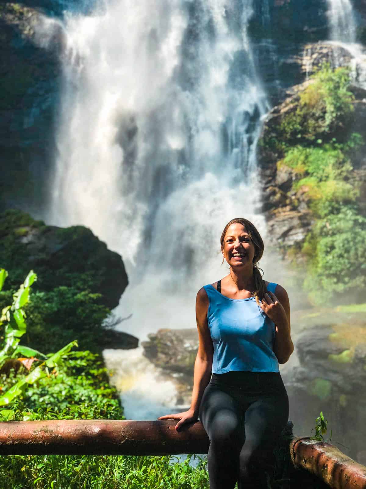 Sitting on a railing in front of a waterfall at Doi Inthanon national park in Chiang Mai