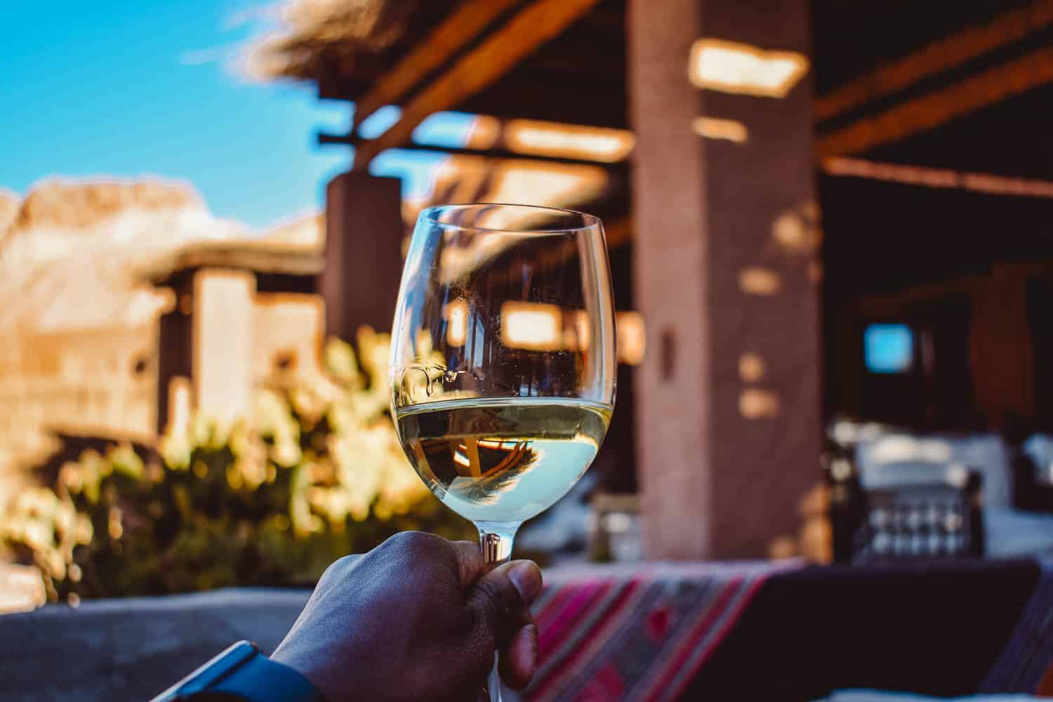 Glass of white wine held up outside in the lounge area at the Alto Atacama hotel