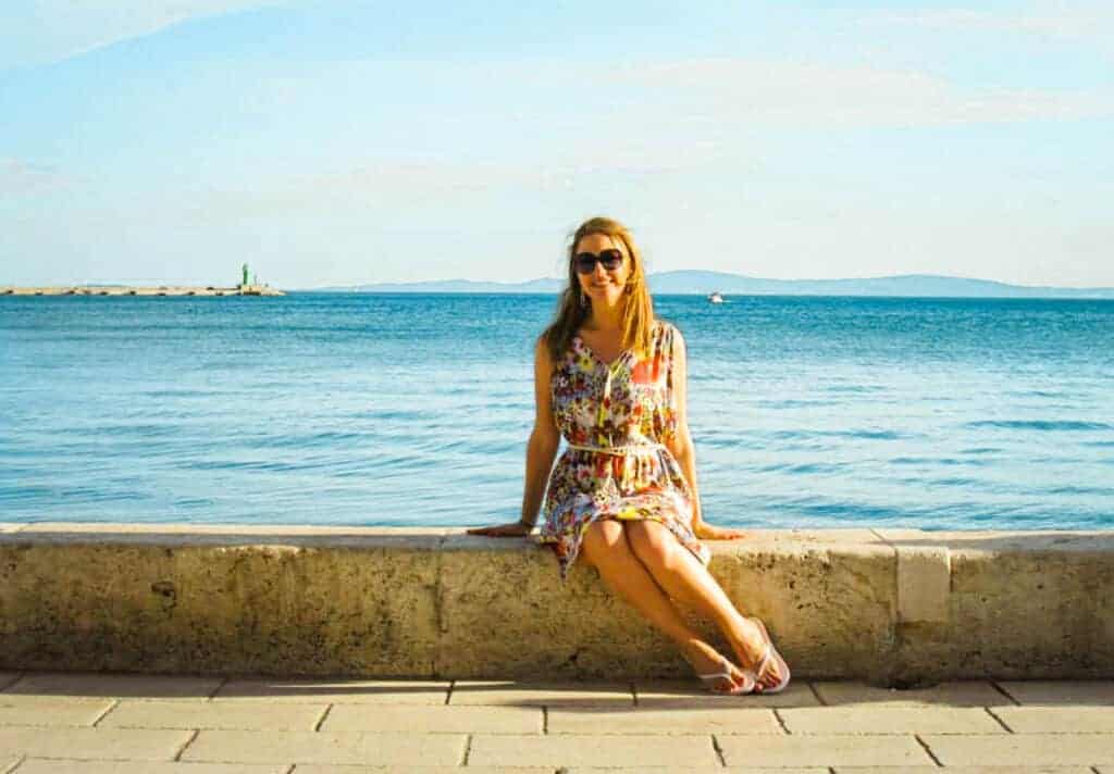 Woman sitting on the a stone wall on the promenade in Split Croatia 