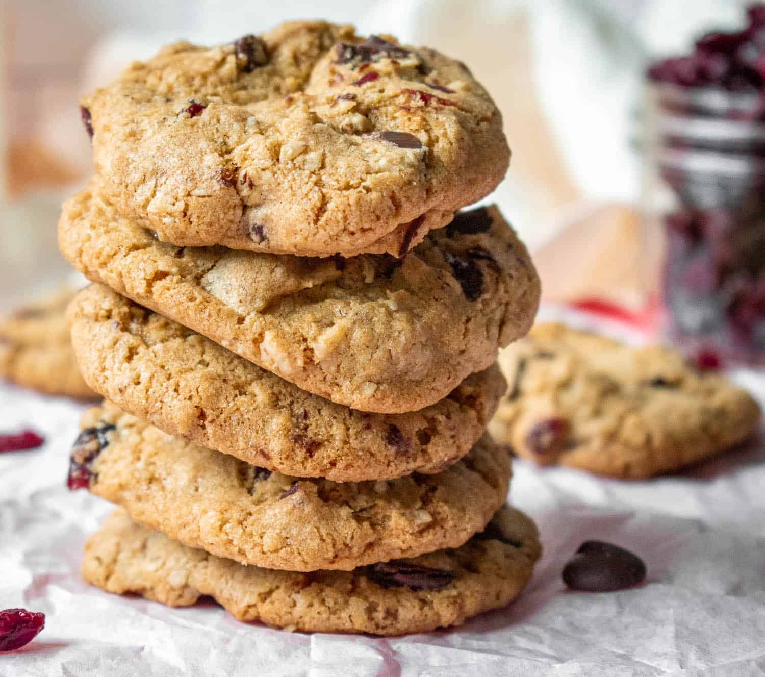 Gluten-free dark chocolate cranberry oatmeal cookies in a stack on a piece of parchment paper. 