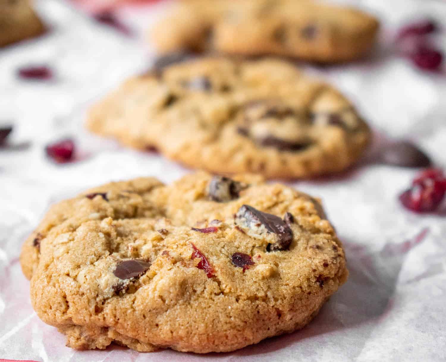 Gluten-free chocolate cranberry cookies in a row on a piece of parchment paper