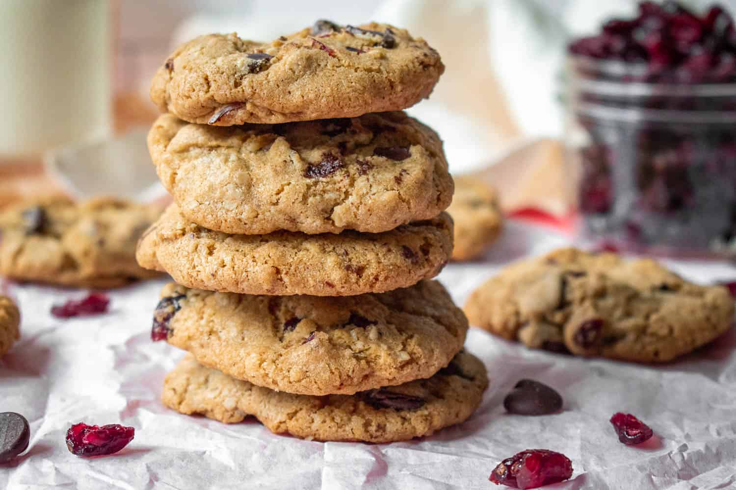 Stack of gluten-free chocolate cranberry oatmeal cookies with a jar of cranberries 