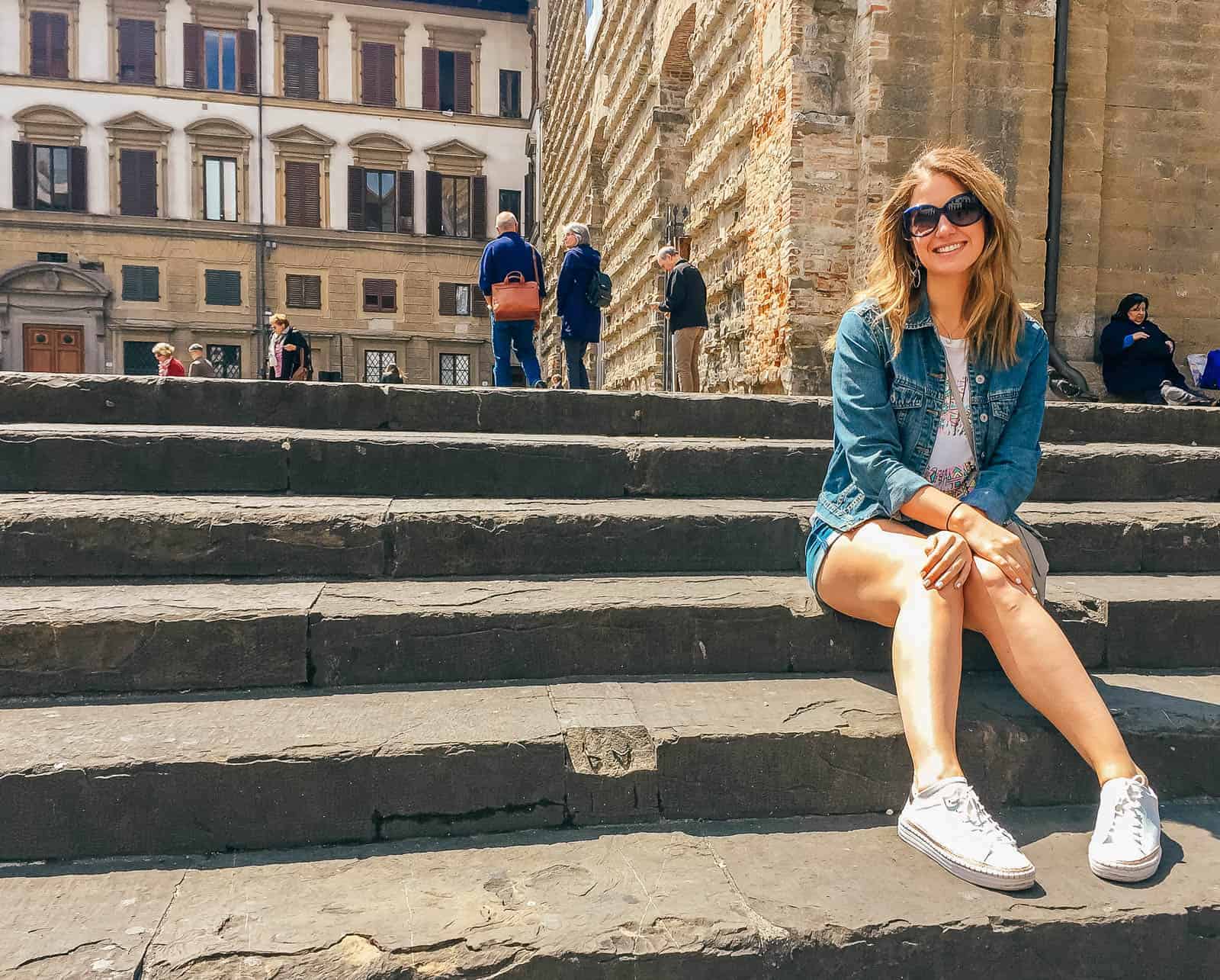 A woman sitting on the steps of Basilica Santa Maria Novella in Florence