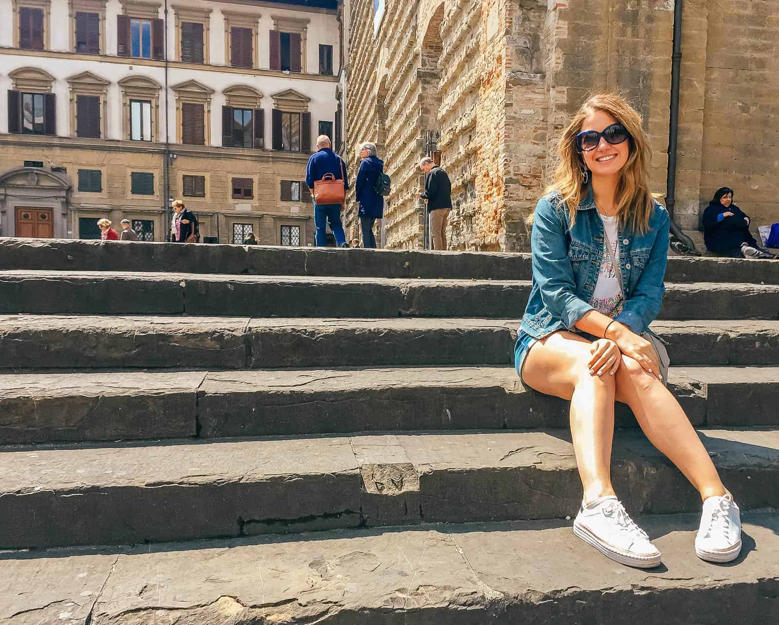 A woman sitting on the steps of Basilica Santa Maria Novella in Florence