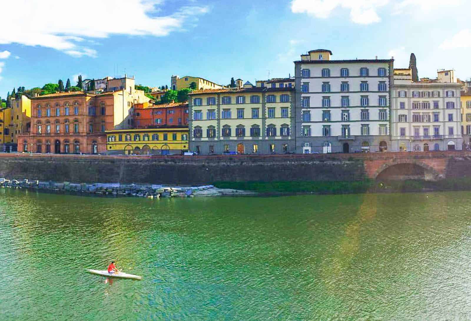 View of someone kayaking on the Arno river spotted during a day trip to Florence