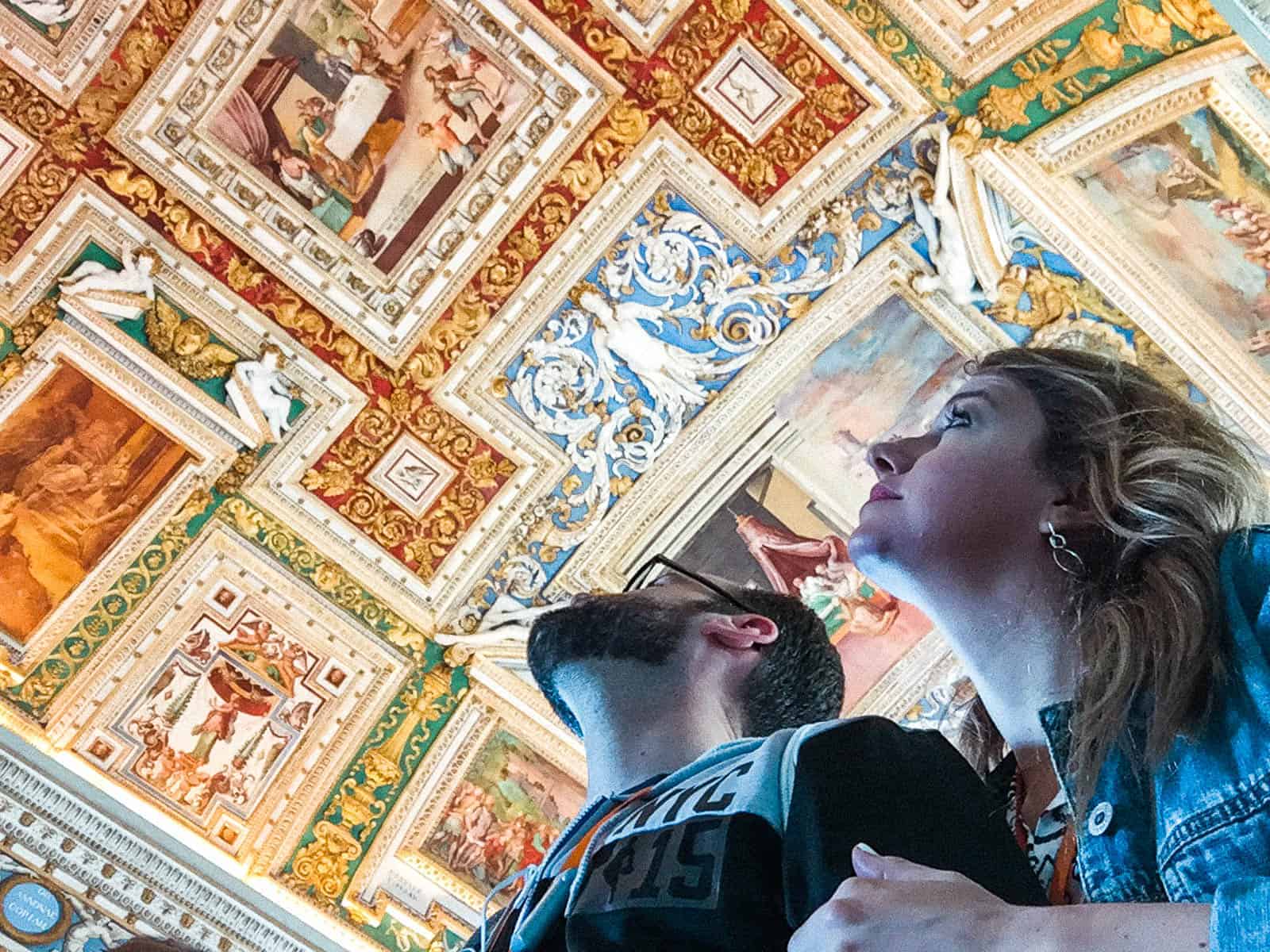 Two people looking up at the ceiling in the hallway of maps at the vatican in rome