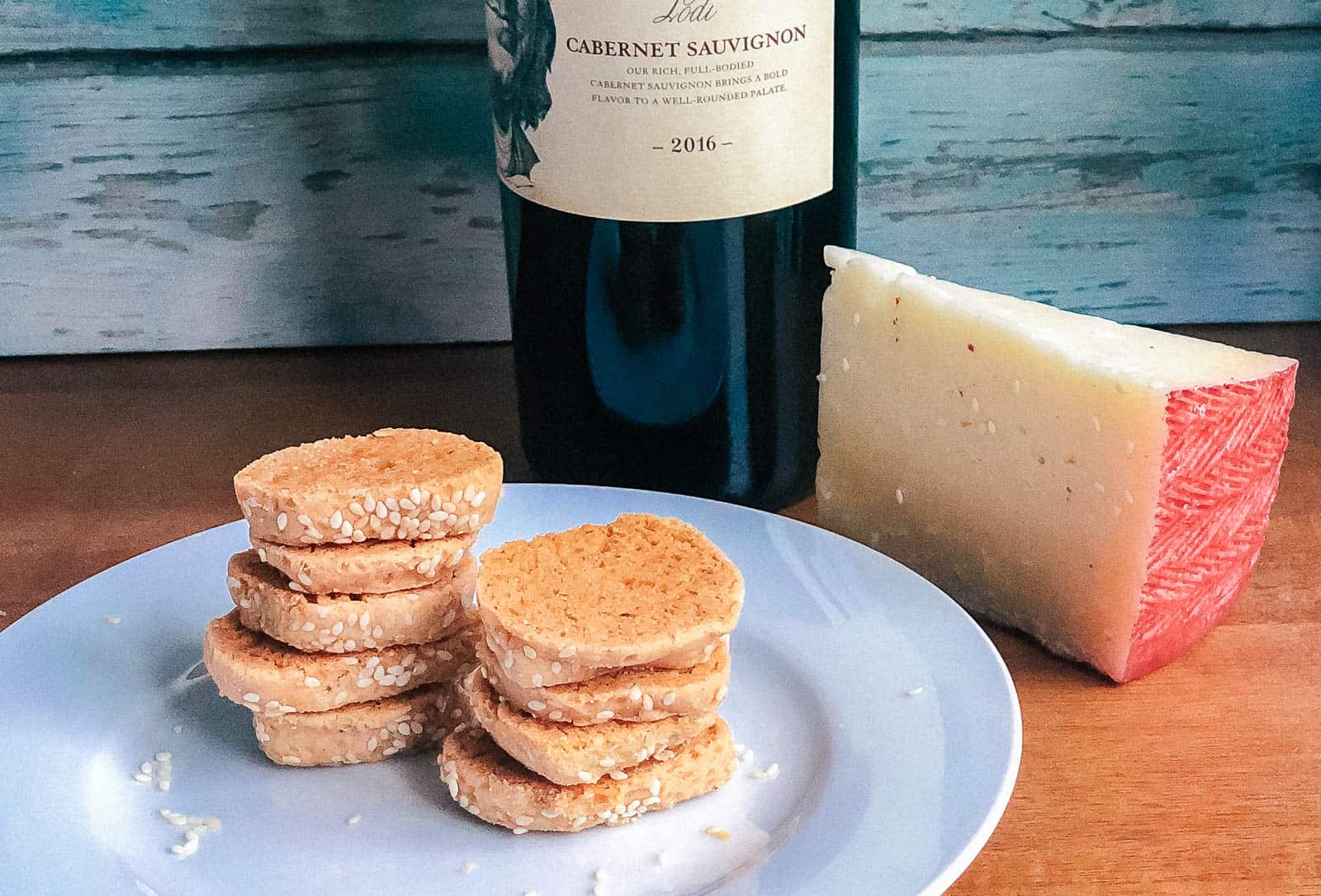 Homemade cheeze-its recipe with a hunk of cheese and bottle of wine