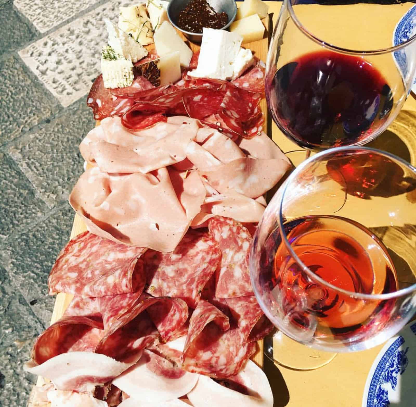 A charcuterie board with a glass of rose on an outdoor table at a restaurant in Lecce, Puglia. 