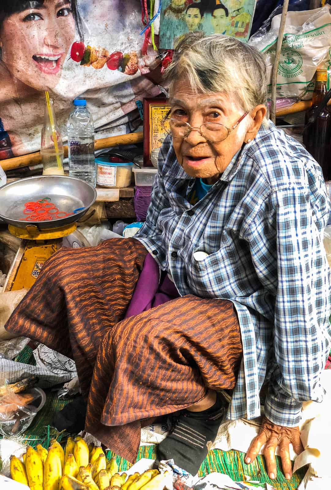 Woman sitting at a stall at Maeklong train market in Bangkok