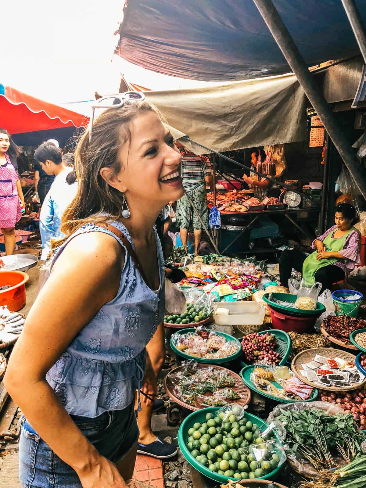 Woman laughing at a food stall at meeklong train market