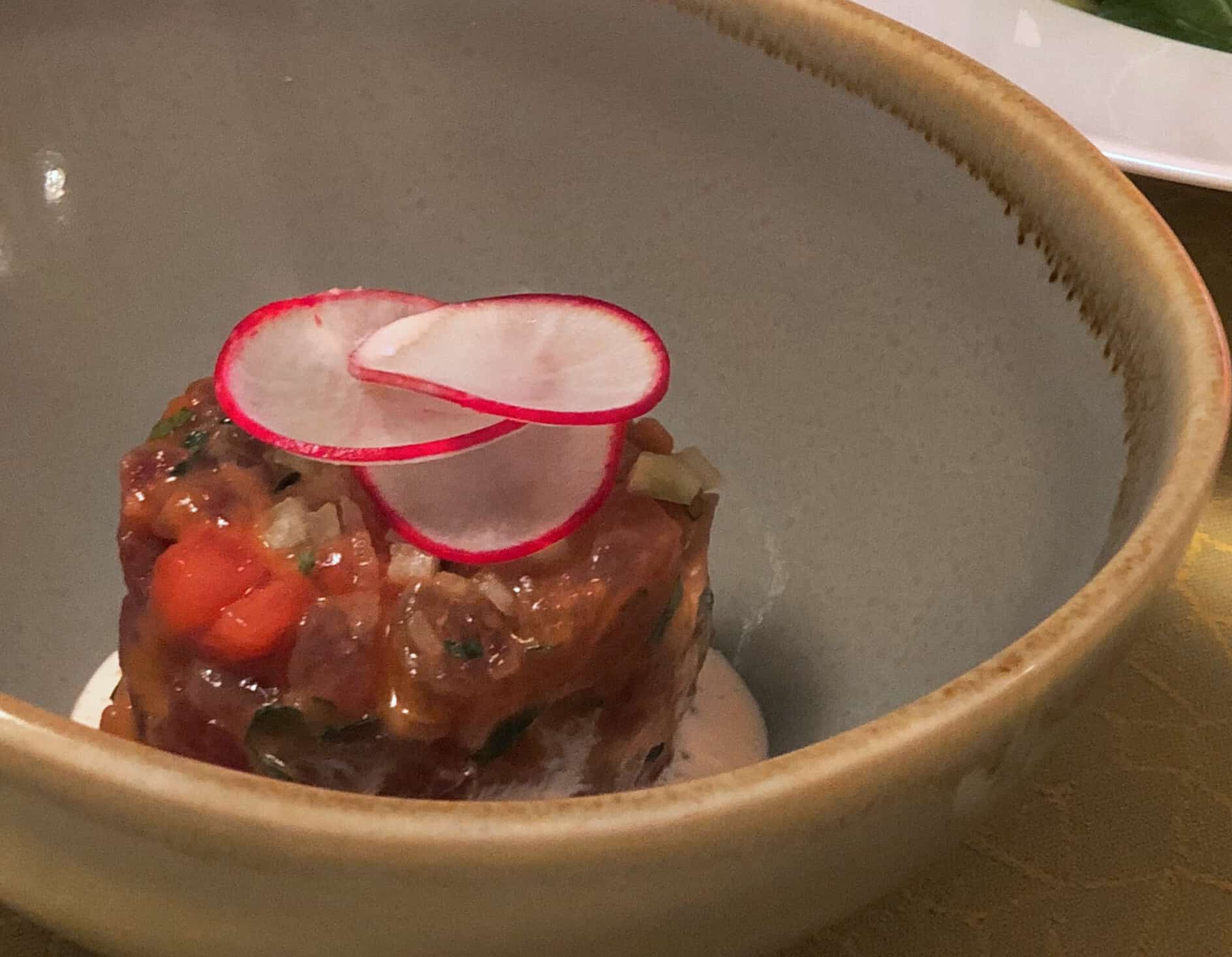 Bowl of tuna tartare with radishes on top. 