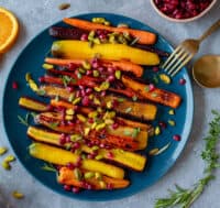 Plate of roasted rainbow heirloom carrots with orange-honey glaze, pomegranate seeds and pistachios.