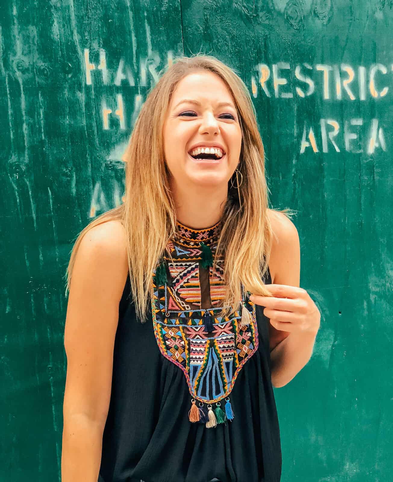 Jess smiling and laughing in front of a green wall