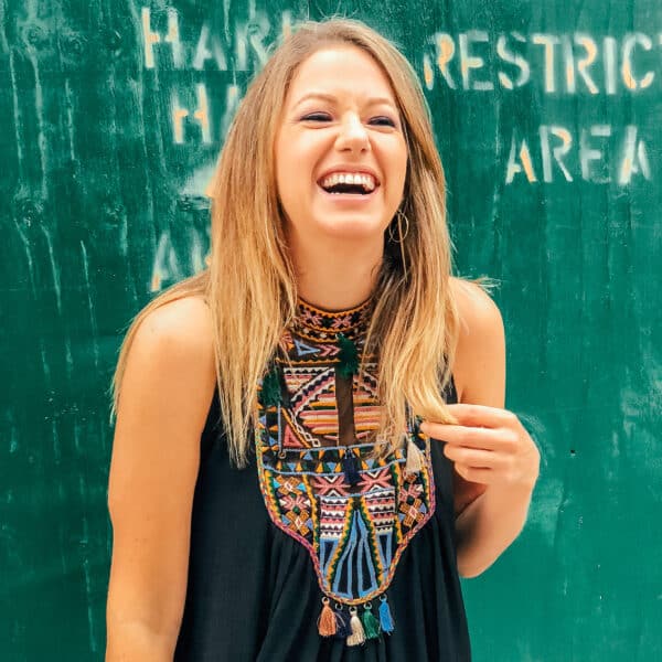 Jess smiling and laughing in front of a green wall