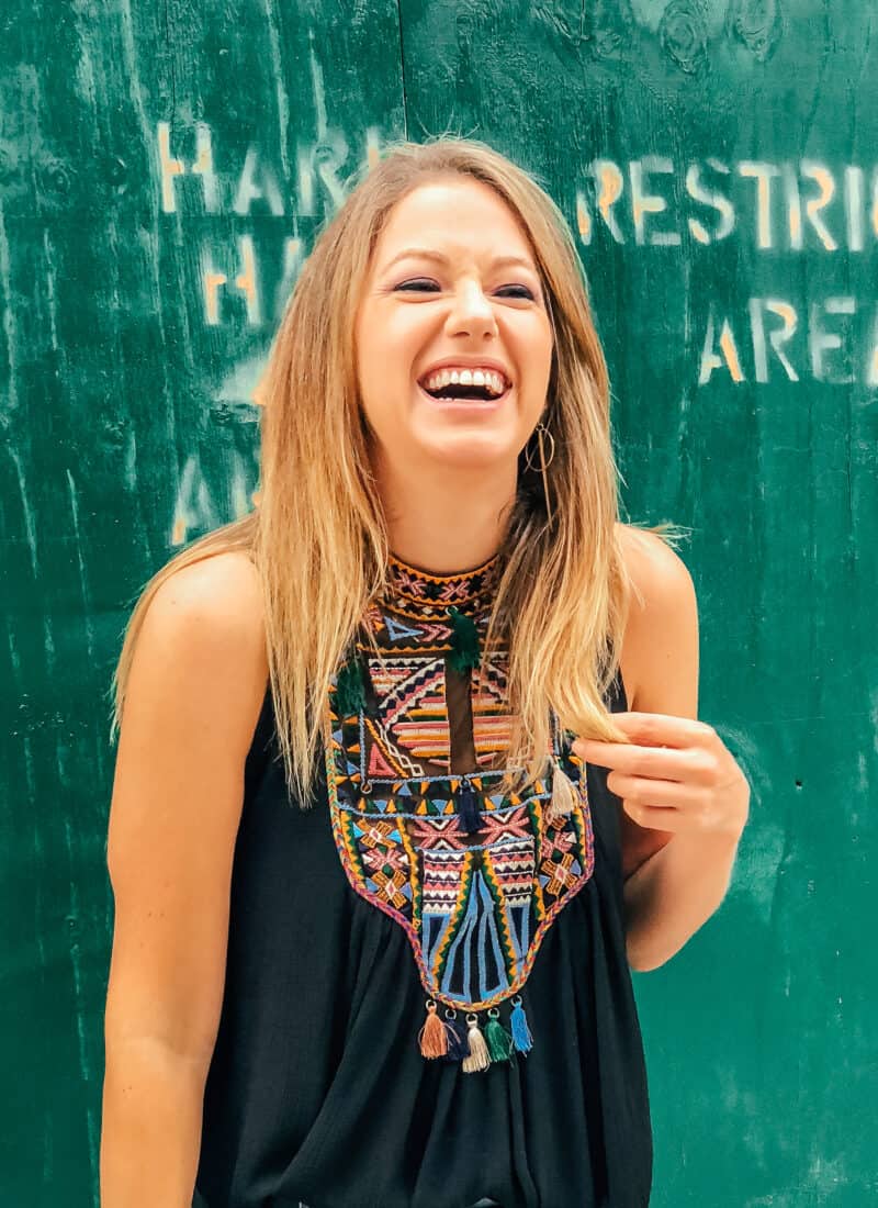 Jess smiling and laughing in front of a green wall