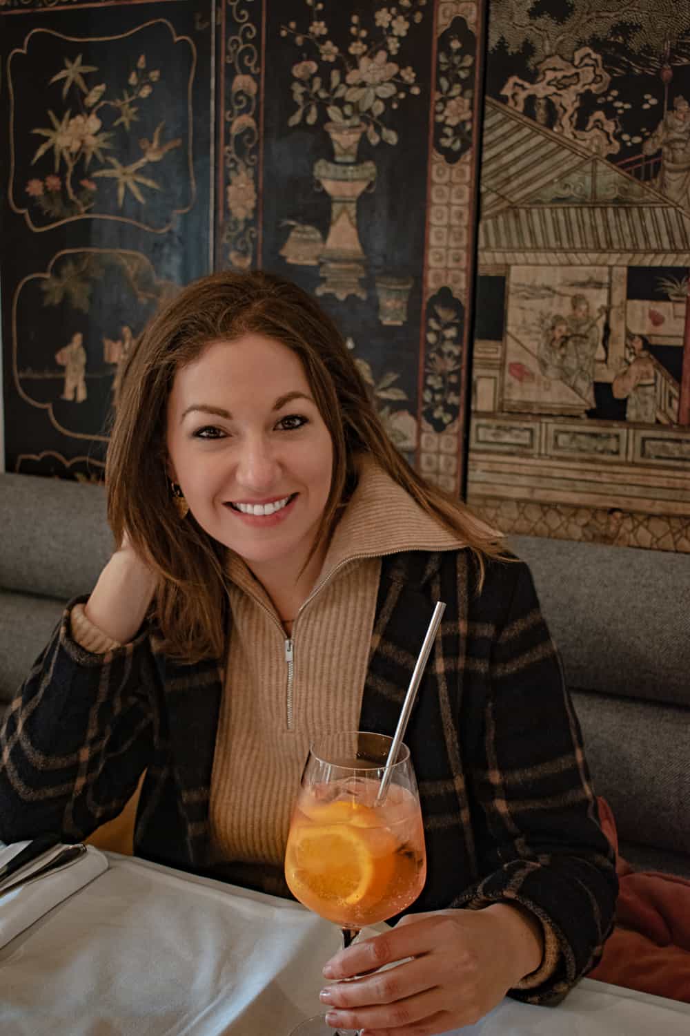 A woman sitting in a restaurant in Paris with an Aperol Spritz