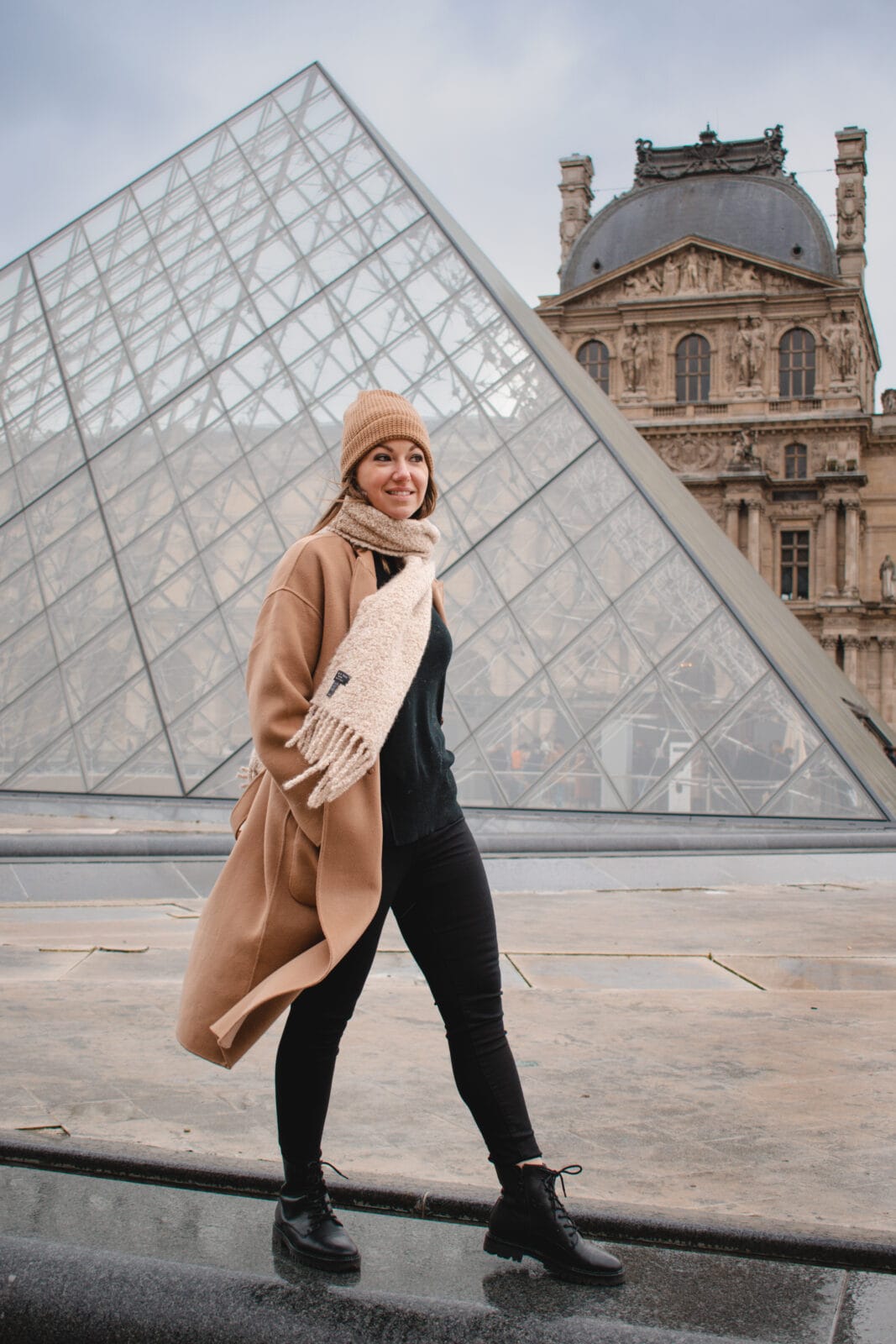 A woman walking outside the Louvre museum in Paris after sightseeing in winter. 