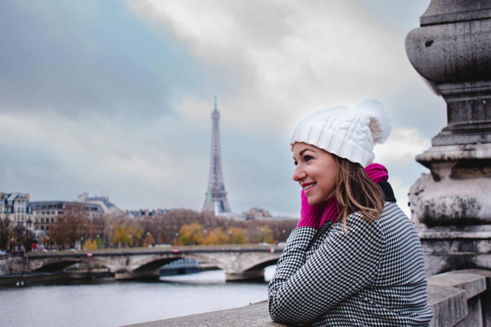 A woman looking at the Eiffel tower from a bridge during a winter trip to Paris