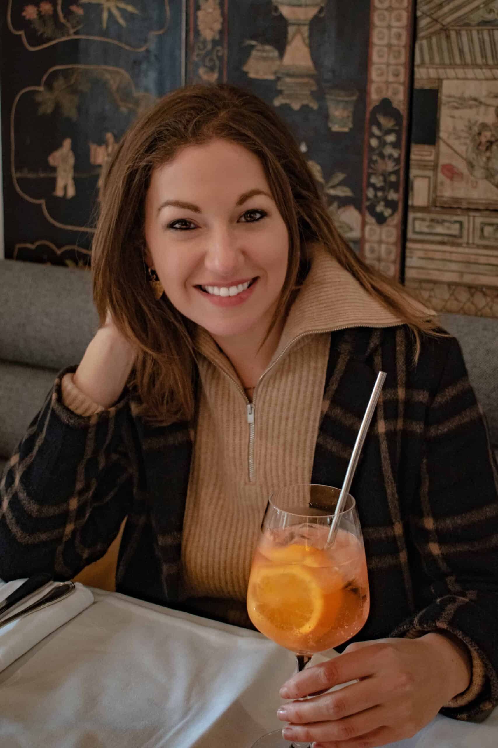 A woman drinking an aperol spritz at a cafe in the Marais while on a winter trip to Paris. 