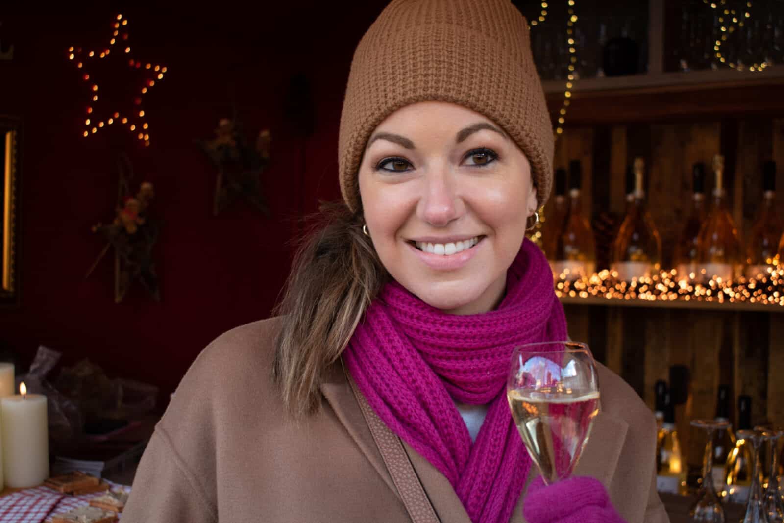 A woman holding a glass of champagne at a Christmas market in Montmartre, Paris. 