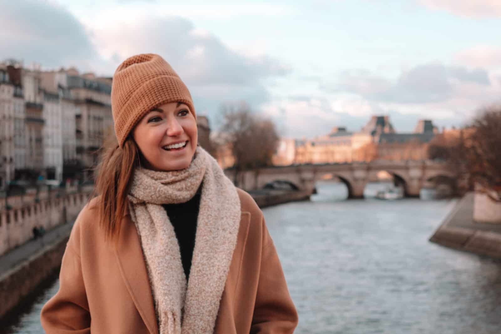 A woman standing on a bridge overlooking the Seine river in Paris during the winter. 