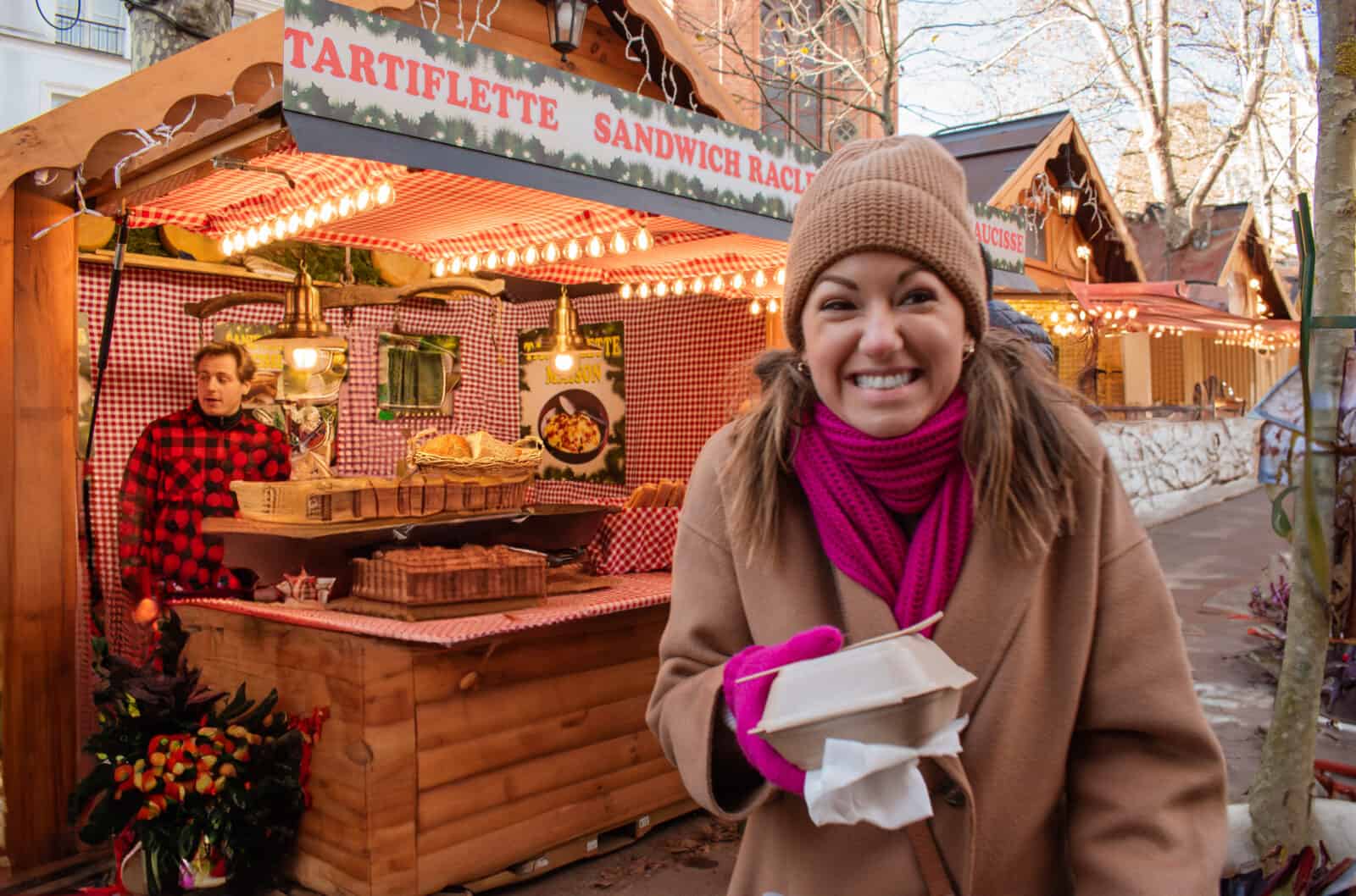 A woman holding a carton of food at the Christmas market in Montmartre in Paris during the winter holiday season. 